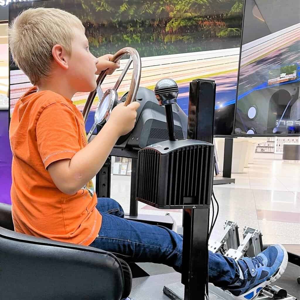 Happy kid enjoying a VR motion racing simulator hire with delivery to London, United Kingdom.